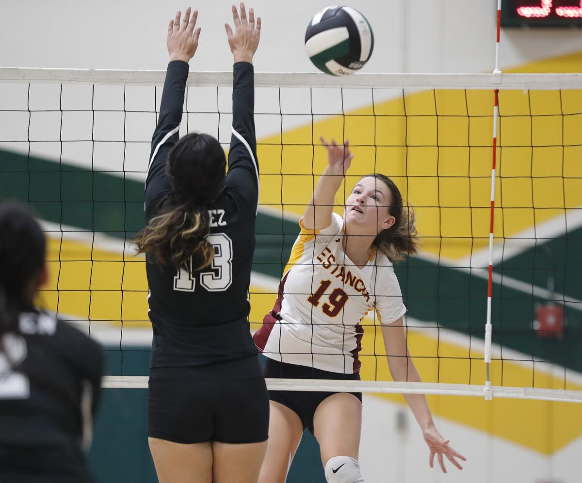 Estancia's Joanna Santosuosso (19) kills the ball past Rancho Alamitos blocker in girls' varsity volleyball on Thursday.
