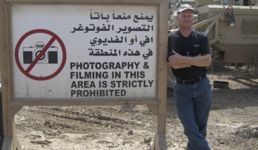 Mark Frerichs, a contractor from Illinois, poses in Iraq next to a sign 