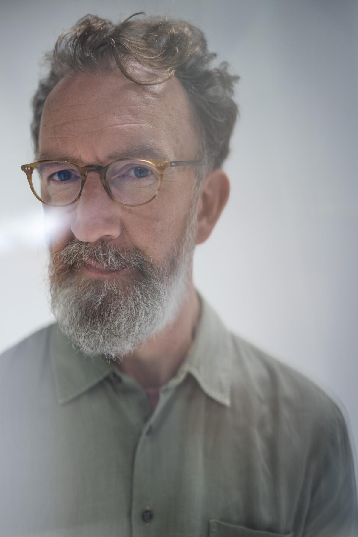 Seen through a prism: A white-bearded, bespectacled man poses for a portrait against a gray background