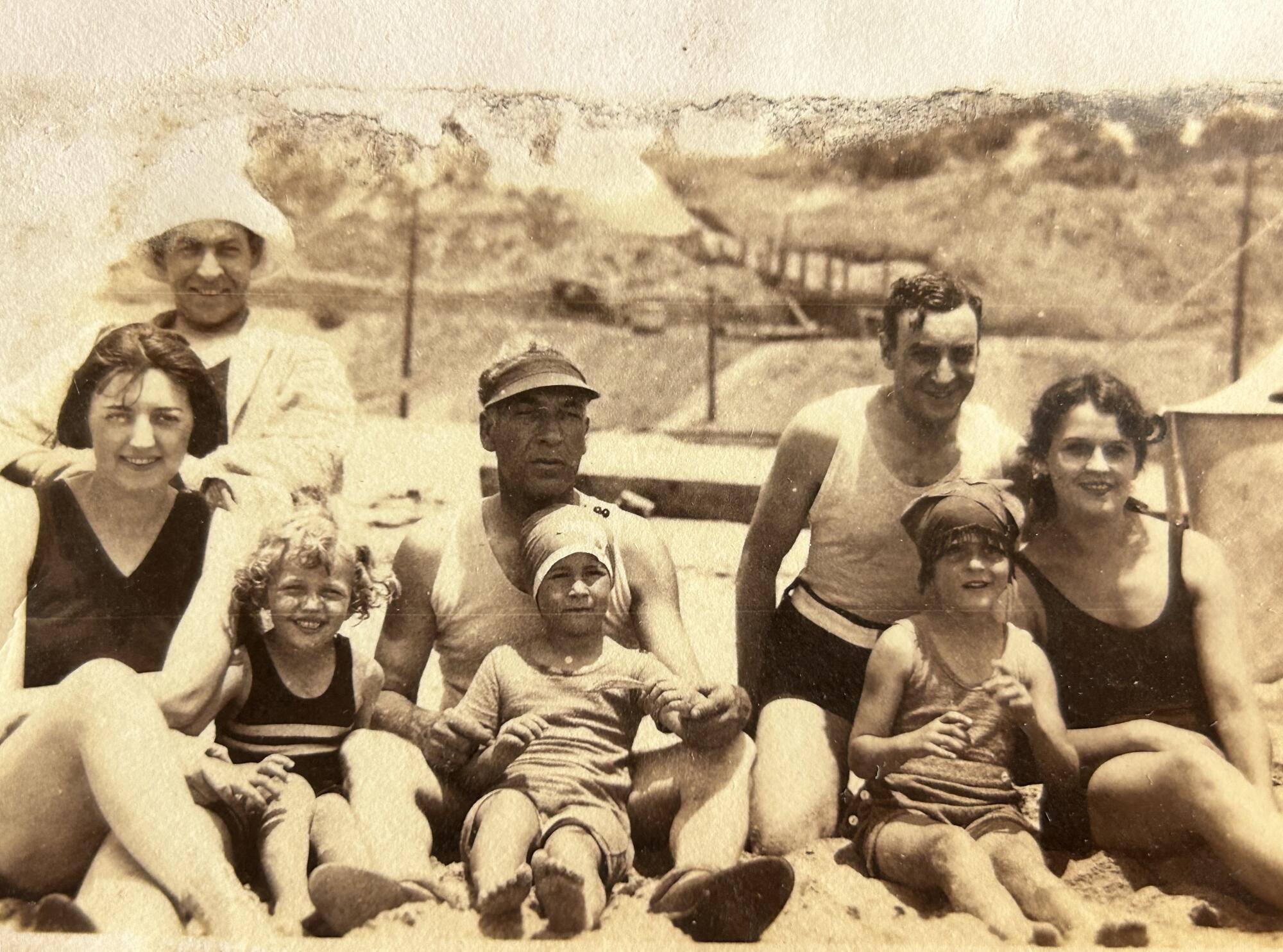 A vintage photo of a family at the beach with five adults and three small children in bathing suits