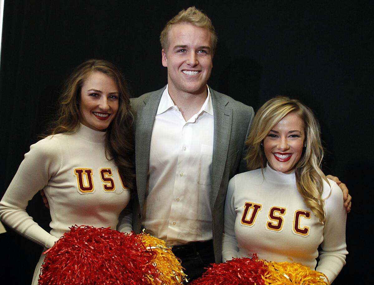 USC quarterback Matt Barkley is flanked by two Song Girls 