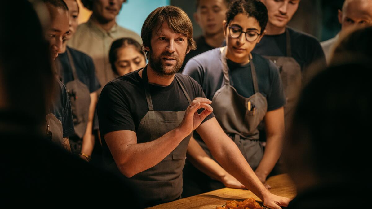 Chef René Redzepi, center, gestures while speaking to employees and wearing an apron