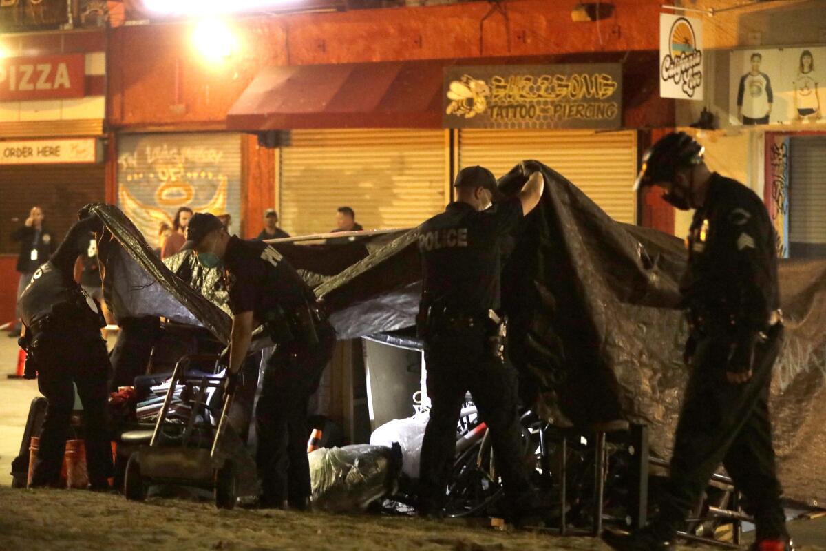 Officers in masks hold up tent covers on a city sidewalk.