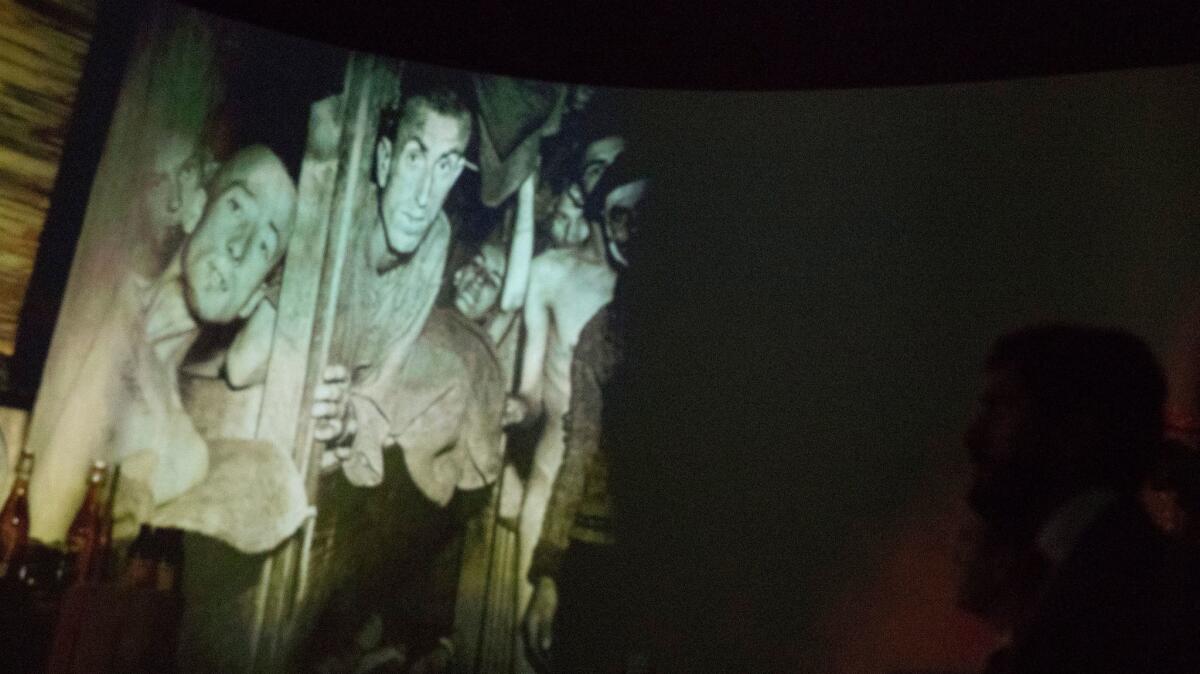 A projection of concentration camp survivors is on a screen as Prince Nasser bin Hamad al Khalifa of the Kingdom of Bahrain tours the Museum of Tolerance.