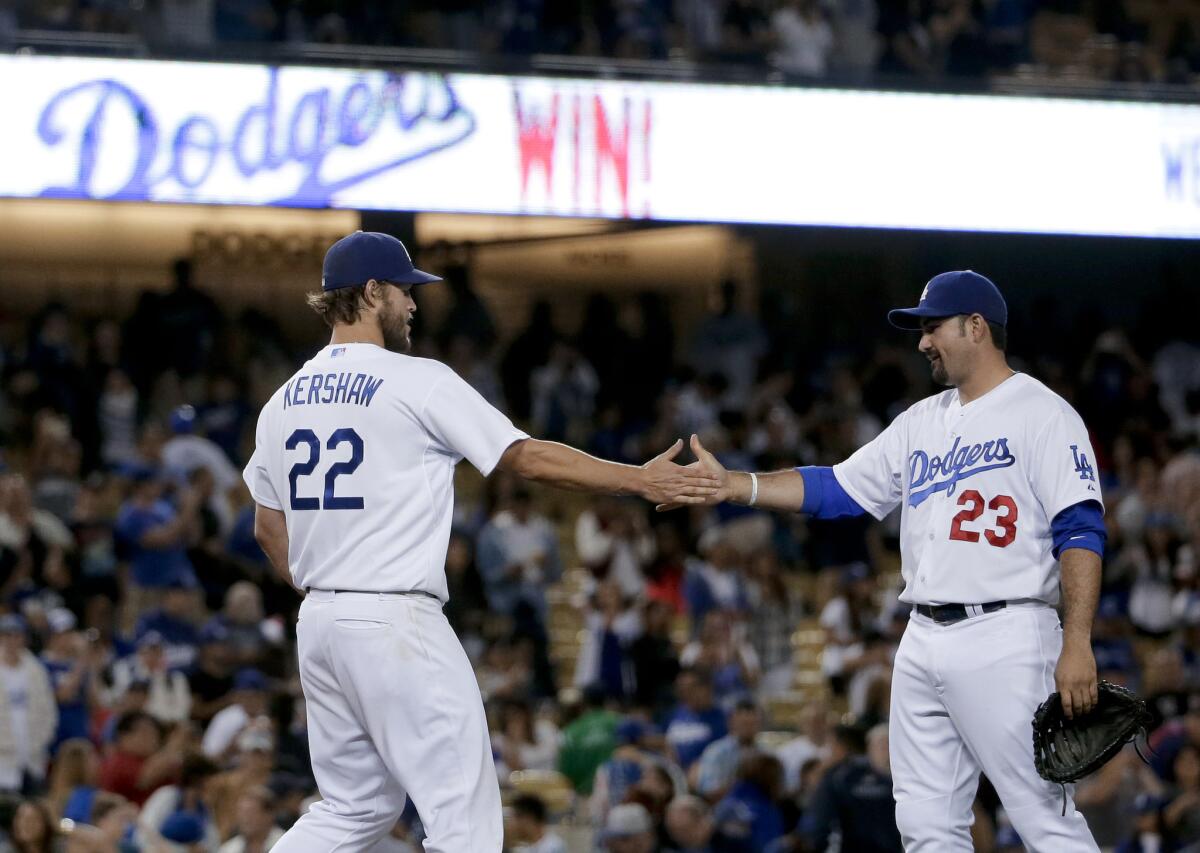 El lanzador de los Dodgers de Los Ángeles, Clayton Kershaw, (izq) choca las manos con el primera base Adrián González el final de un partido contra los Filis de Filadelfia.