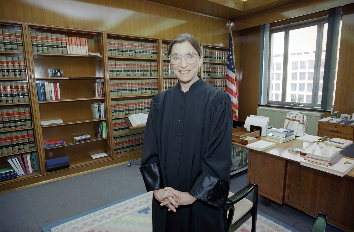 Then-judge Ruth Bader Ginsburg poses in her robe in her office at U.S. District Court in Washington