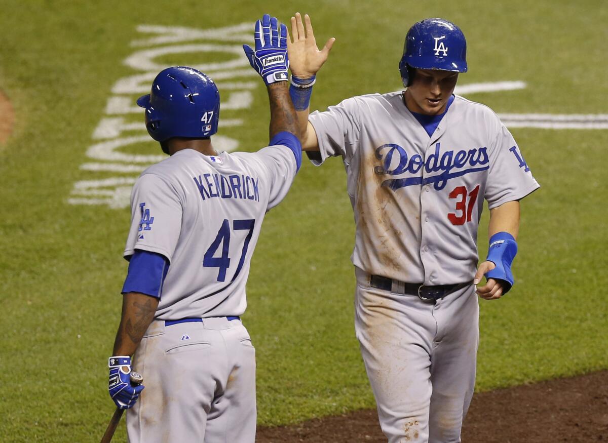 Dodgers center fielder Joc Pederson (31) gets a high-five from second baseman Howie Kendrick after scoring on a double by third baseman Justin Turner in the fifth inning in Denver on June 3.