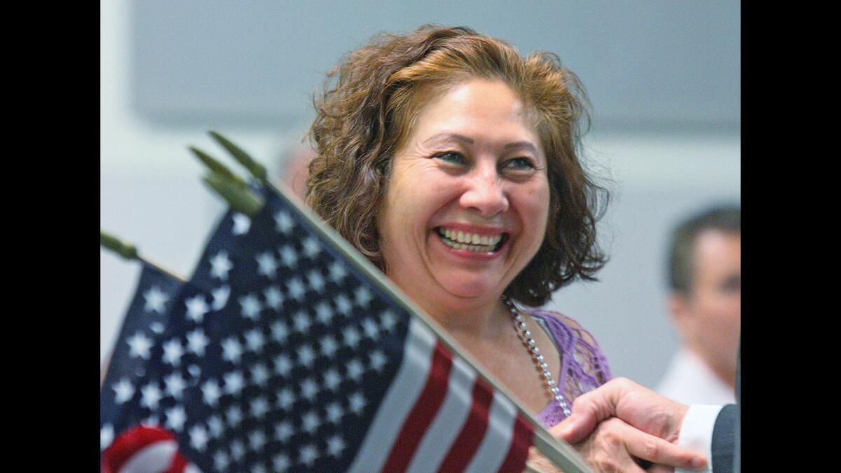 Angelia Castillo smiles as she shakes hands with Abraham Lincoln, receiving an American flag and pin at a ceremony recognizing students who recently became U.S. citizens at the Glendale Community College Garfield campus on Thursday, April 21, 2016.