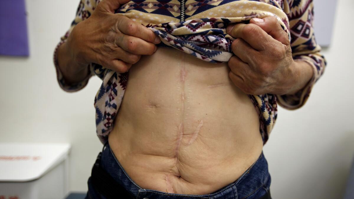 A homeless woman named Karen reveals scars from a stabbing during an exam.