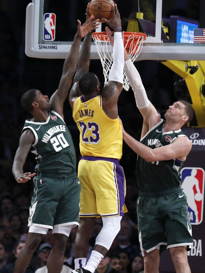 LeBron James dunks on Bucks forward Marvin Williams (20) and center Brook Lopez (11) during the first half of a game March 6 at Staples Center.