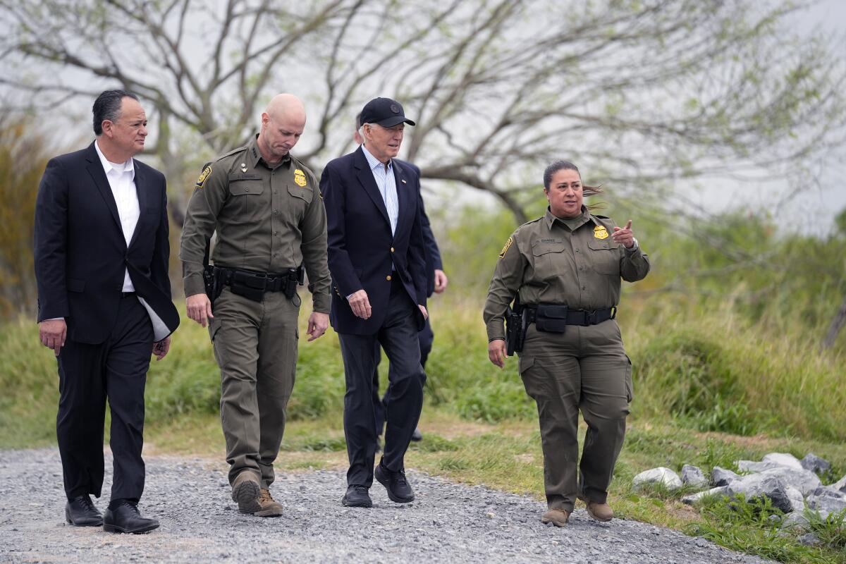 Four people walk along the southern border in Brownsville, Texas