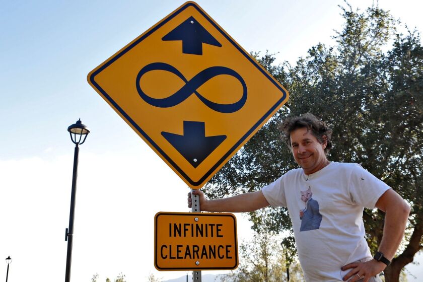 Artist Scott Froschauer stands next to his "Infinite Clearance" street sign artwork at Deukmejian Wilderness Park in Glendale, on Tuesday, Nov. 7, 2017.