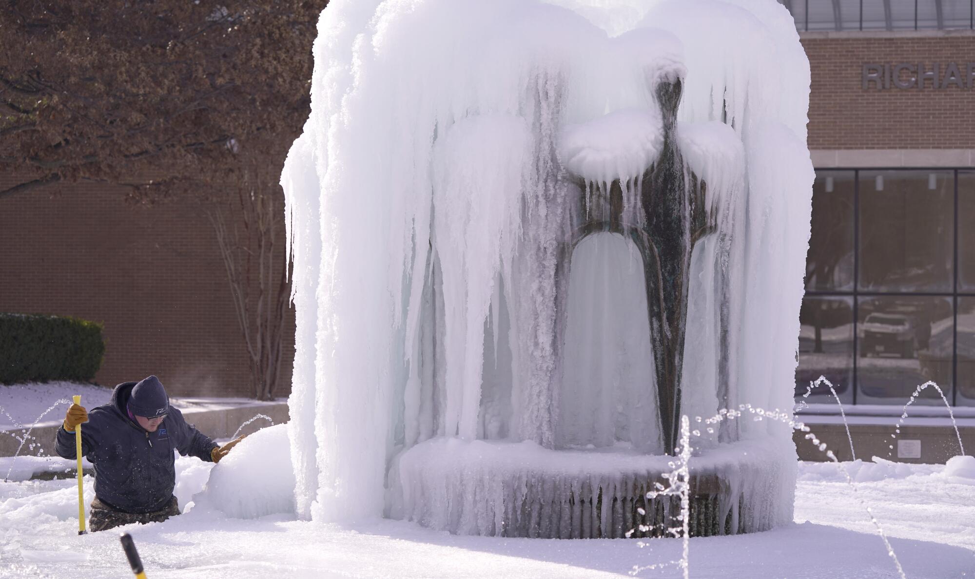 A worker tries to clear ice from a fountain. 