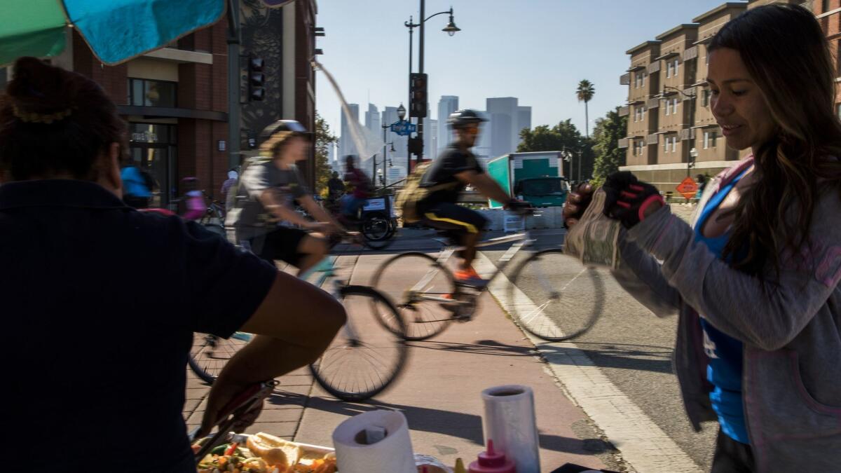 A vendor sells hotdogs as cyclists take to the streets in Boyle Heights.