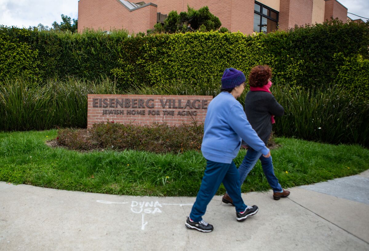 People walk past Eisenberg Village nursing home where they are screening all incoming for symptoms of the coronavirus in Reseda.