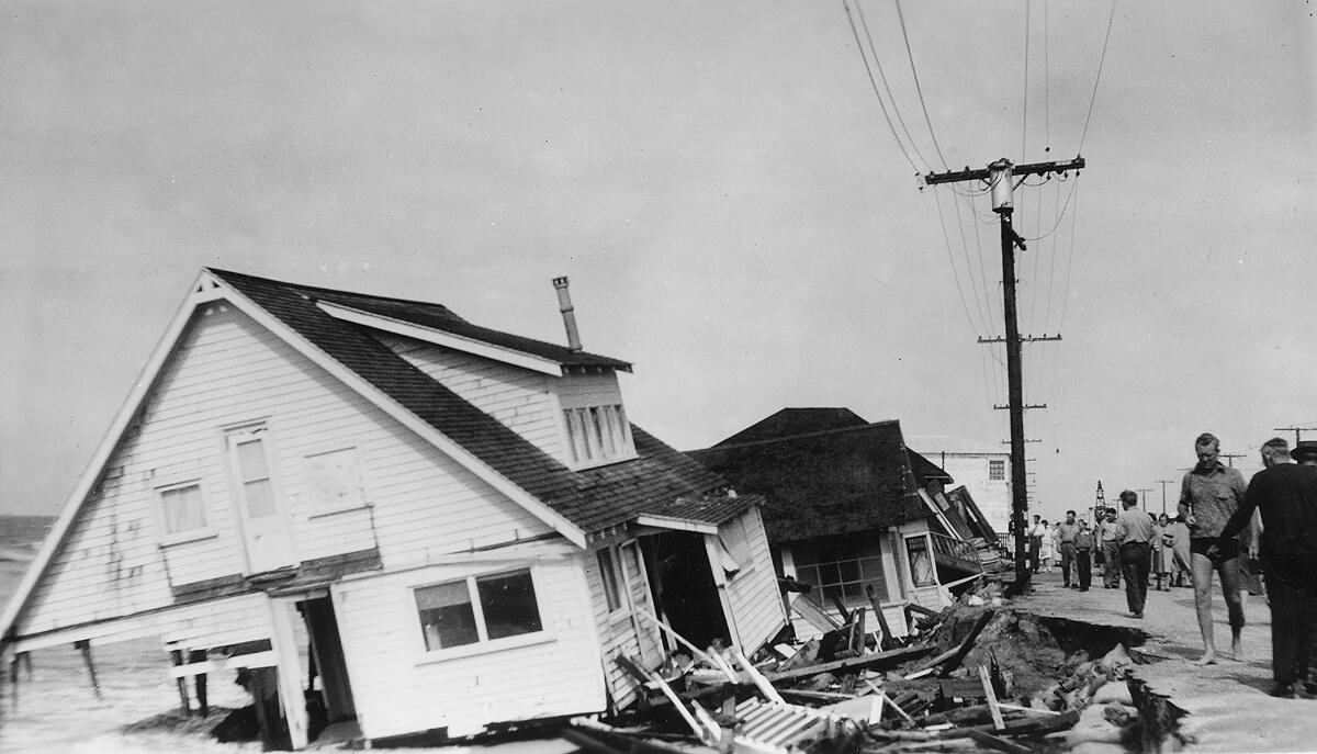 Bystanders view a collapsed home.