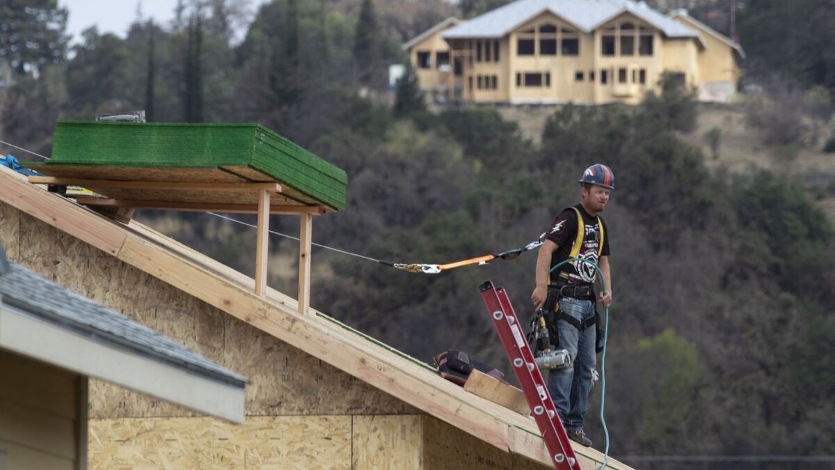 A roofer waits for supplies on a roof in Mark West Estates on Oct. 10 in Santa Rosa.
