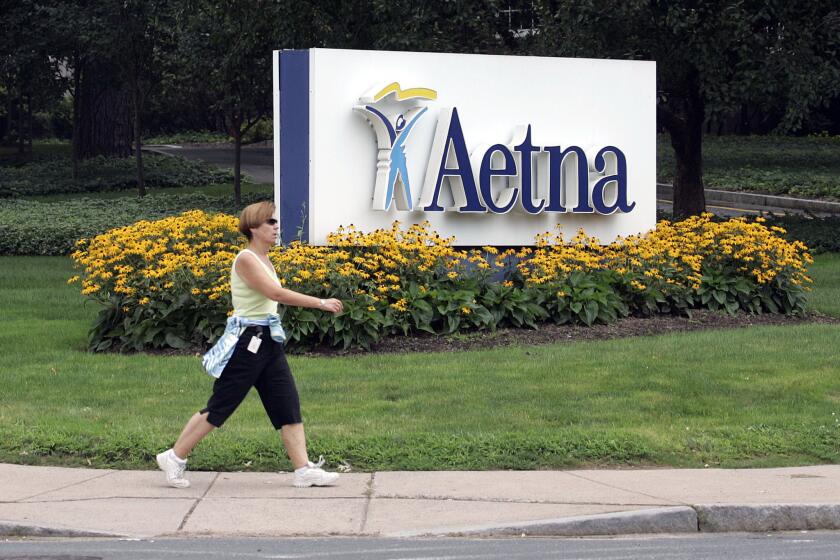 A woman strides past the Hartford, Conn., headquarters of Aetna, Inc.