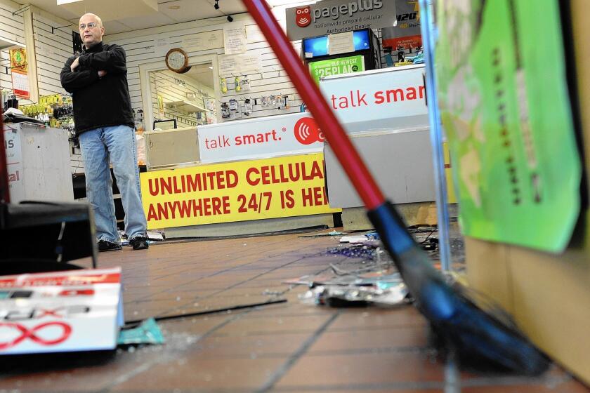 Sonny Dayan looks over his losses as friends help him clean up his cellphone shop on West Florissant Avenue in Ferguson, Mo. His shop was damaged in Monday night's rioting, as it had been during the unrest after the shooting of Michael Brown on Aug. 9.