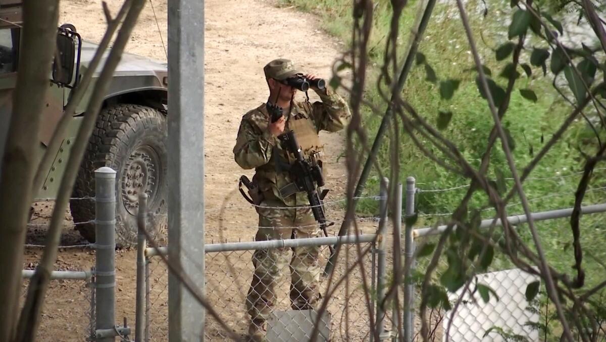 A National Guard troop watches over Rio Grande River on the border in Roma, Texas.