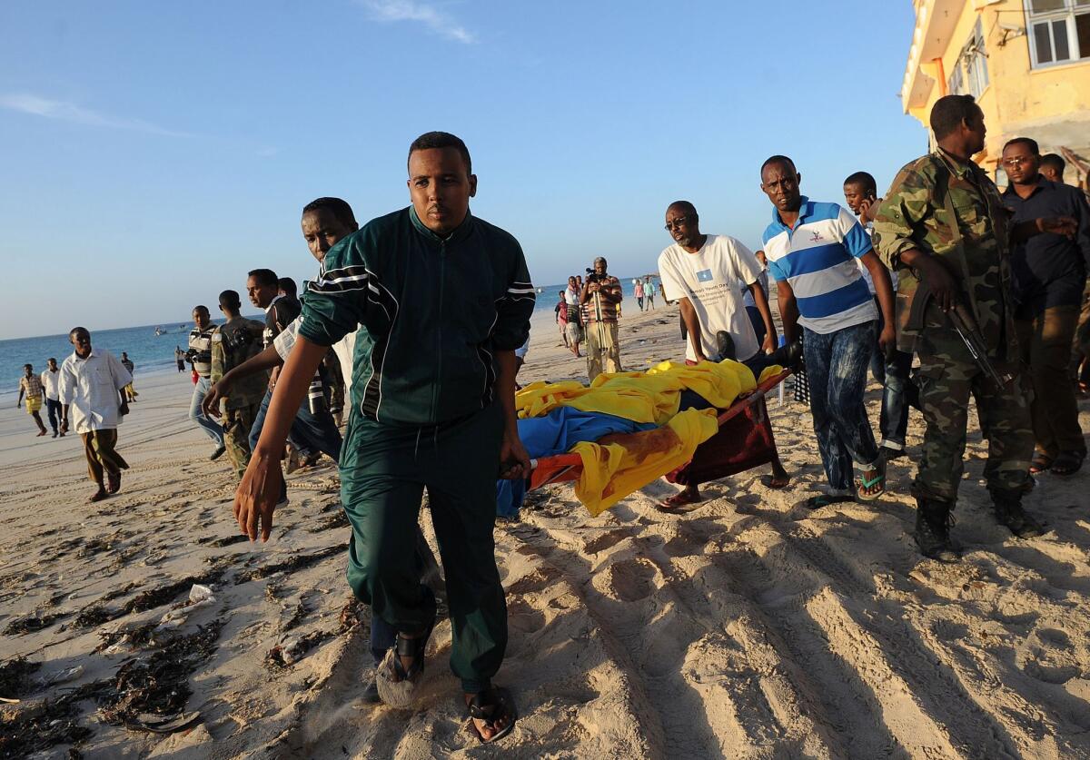 People carry away a dead body from Liido beach following an overnight attack on a beachfront seafood restaurant in Mogadishu.