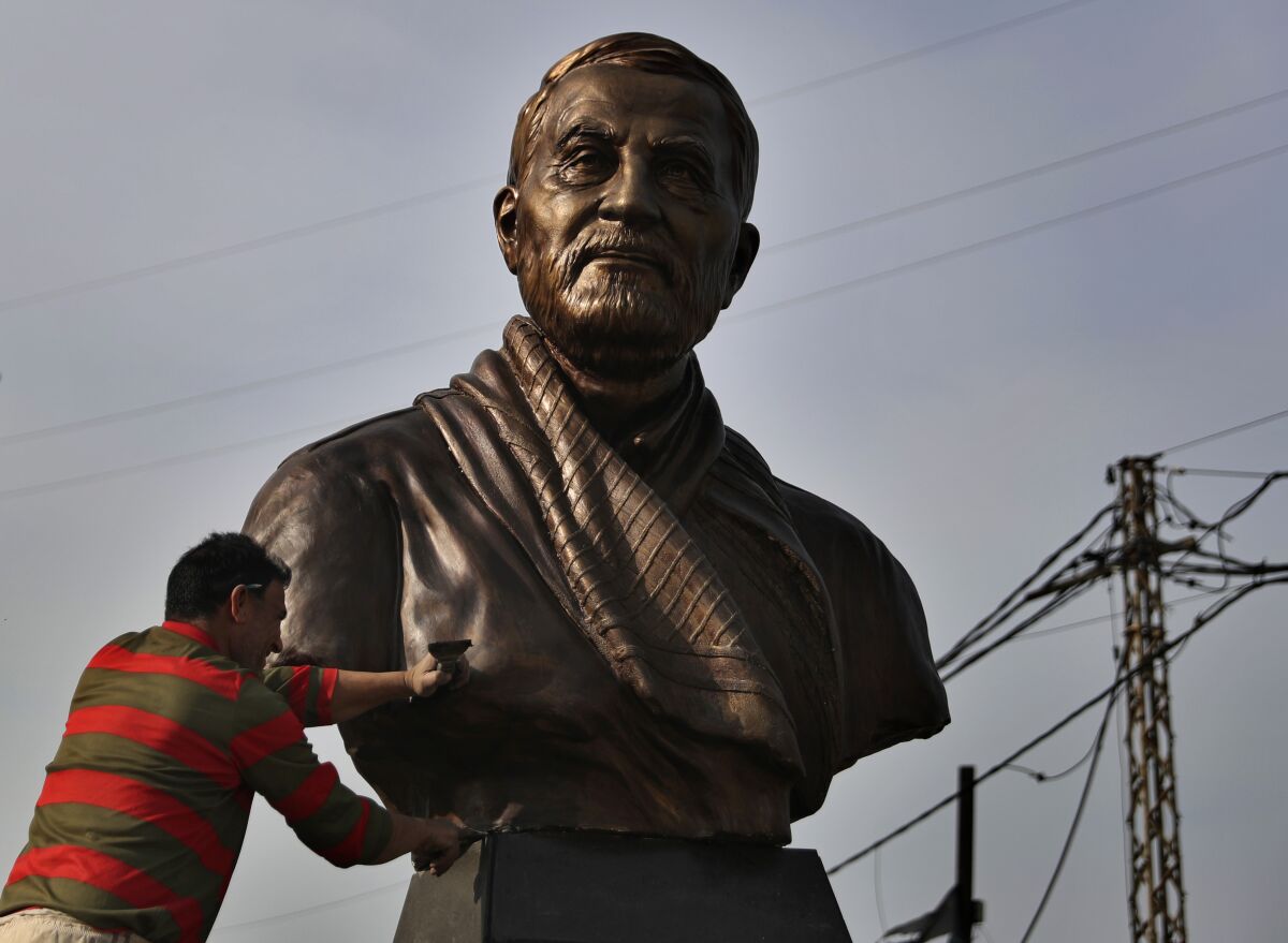 A worker cleans a statue of Iranian General Qassem Soleimani, installed to commemorate the anniversary of his killing, in a U.S. drone strike in Baghdad, in Ghobeiry, a southern suburb of Beirut, Lebanon, Wednesday, Jan. 6, 2021. (AP Photo/Bilal Hussein)