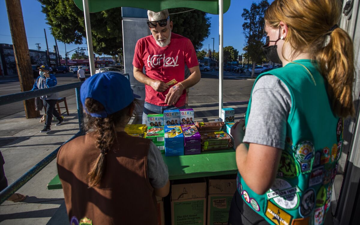 Chris Hillman buys Girl Scout Cookies from Madar Mee and Emma Diaz