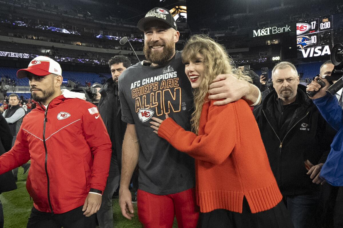 ARCHIVO - El tight end de los Chiefs de Kansas City Travis Kelce camina con Taylor Swift