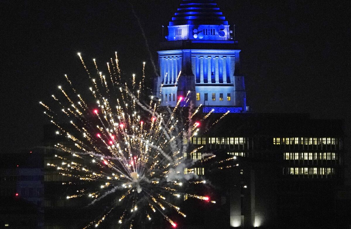 FILE - In this Oct. 27, 2020, file photo, Los Angeles City Hall is illuminated with dark blue lights as Dodgers fans celebrate with fireworks on Sunset Boulevard after watching the broadcast of Game 6 of the baseball World Series in Los Angeles. A Southern California official is seeking federal help in stopping an influx of illegal fireworks that has fueled use of skyrockets and firecrackers well beyond July 4 and led to the deadly explosion of a cache in the middle of a neighborhood this year. (AP Photo/Damian Dovarganes, File)