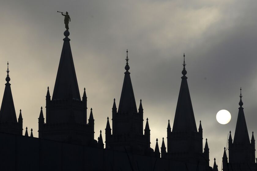 FILE - The angel Moroni statue atop the Salt Lake Temple is silhouetted against a cloud-covered sky, at Temple Square in Salt Lake City on Feb. 6, 2013. (AP Photo/Rick Bowmer, File)
