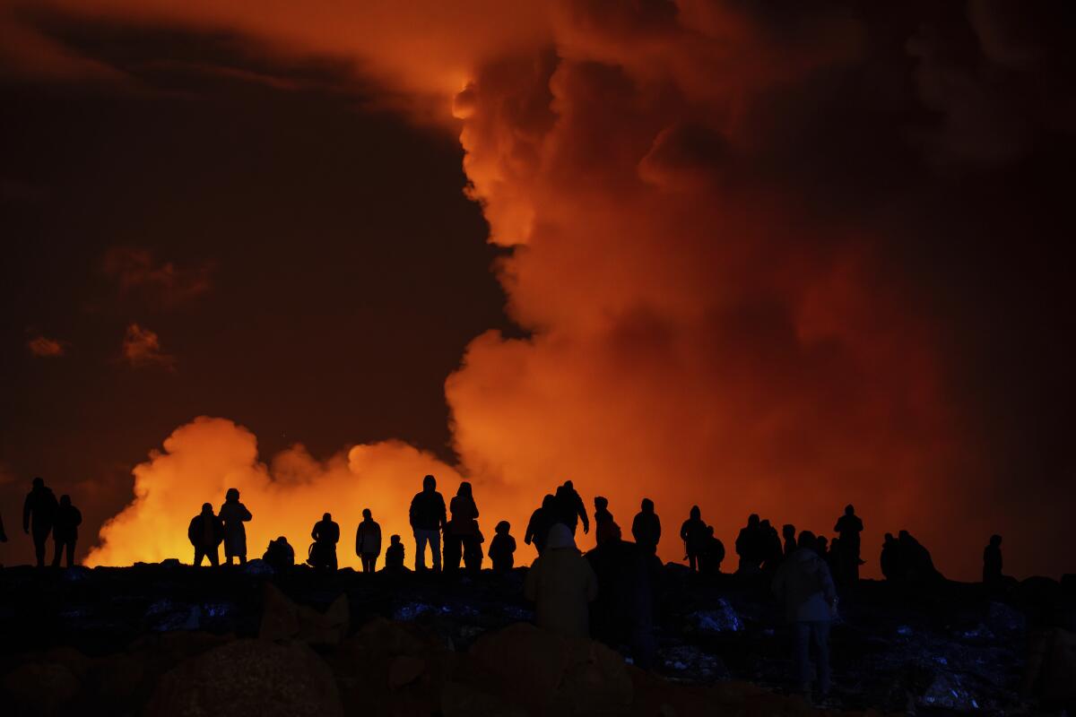 Spectators watch plumes of smoke from volcanic activity at night