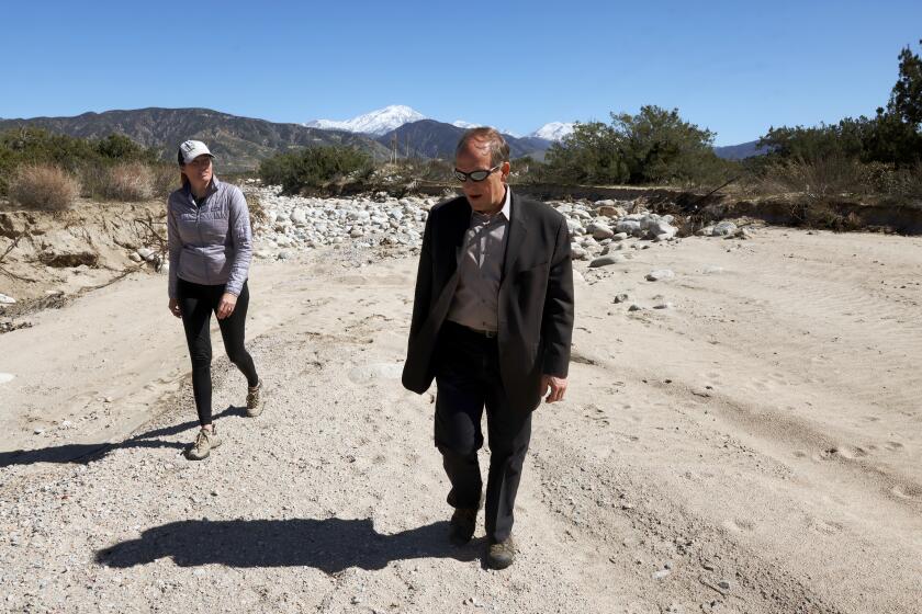 SAN BERNARDINO, CA - FEBRUARY 24: Conservation spokespeople Betsy Miller, left, and Daniel Cozad, right, walk in a flood control channel in the San Bernardino Valley Water Conservation District's Plunge Creek Project zone in Highland on Thursday, Feb. 24, 2022 in San Bernardino, CA. The project includes 5,000 acres of habitat in the city of Highland set aside for a rare kangaroo rat. (Dania Maxwell / Los Angeles Times)