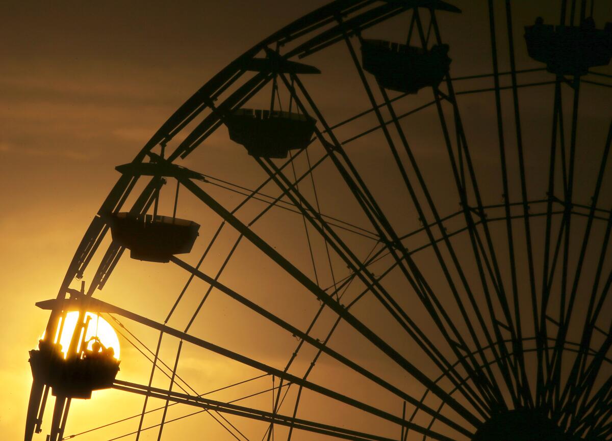 A Ferris wheel is silhouetted against the setting sun at Santa Monica Pier