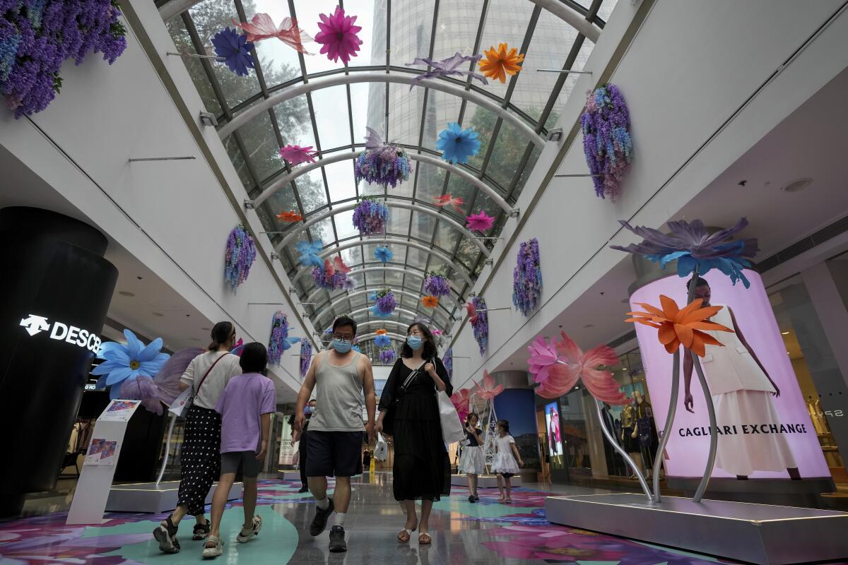 People in masks walk through a shopping mall.