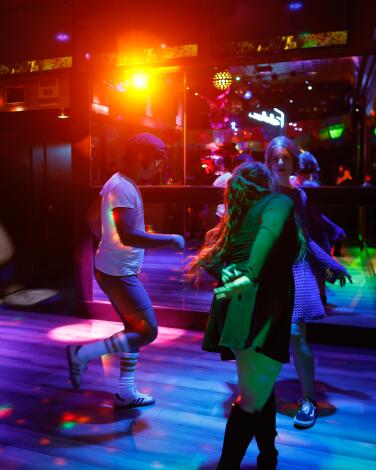 People dance on a colorfully lighted dance floor.