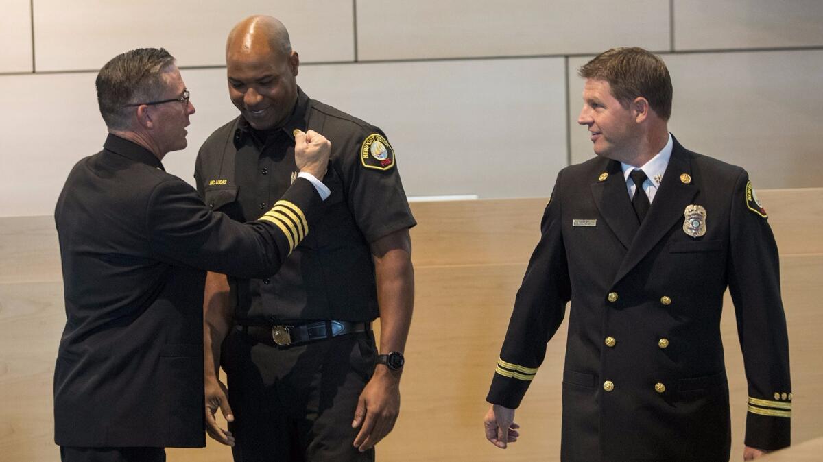Fire Chief Chip Duncan, left, congratulates newly promoted Battalion Chief Nic Lucas as new Assistant Fire Chief Jeff Boyles looks on during a Newport Beach Fire Department promotion ceremony Tuesday.