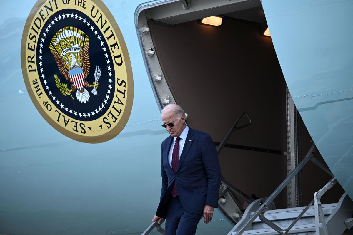 The president walks down the stairs of his jet.