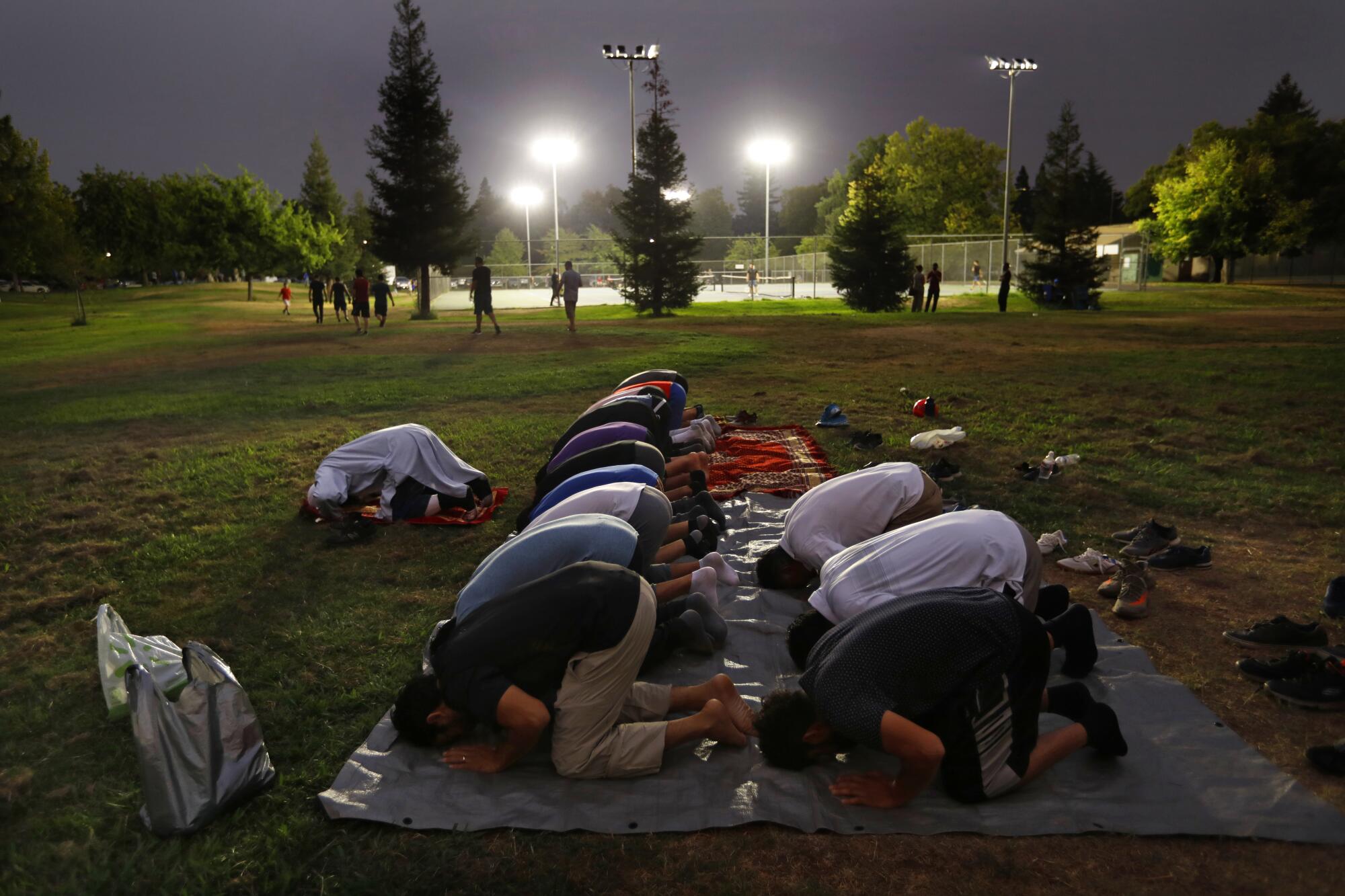 Afghan men gather in prayer at a park 