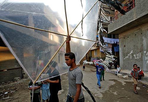 Children get ready to fly a kite in a side street of the al-Sayida Aisha area of old Cairo. Egyptian children fly them for fun as a tradition in poor neighborhoods. Its nice and cool at sunset. There are days when you cant see the sky because there are so many kites, and sometimes we fly at night, tying little lanterns on them, says kite enthusiast Hani Mahmoud.