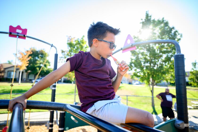 PITTSBURG, CALIFORNIA - OCT 14: Ezekiel Martinez, 7, eats a baby food pouch while his father watches at a park in Pittsburg, California on October 14, 2024. Sales of baby food pouches have increased 900% over the past decade and account for nearly half of infant food sold. (Josh Edelson / For the Times)