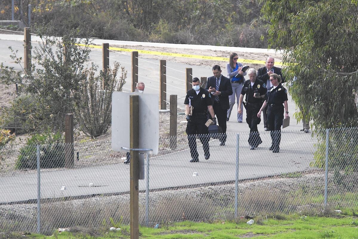 Investigators walk a bike path near the 405 Freeway in Irvine where a body was found Jan. 19. A suspect has been identified in the case.