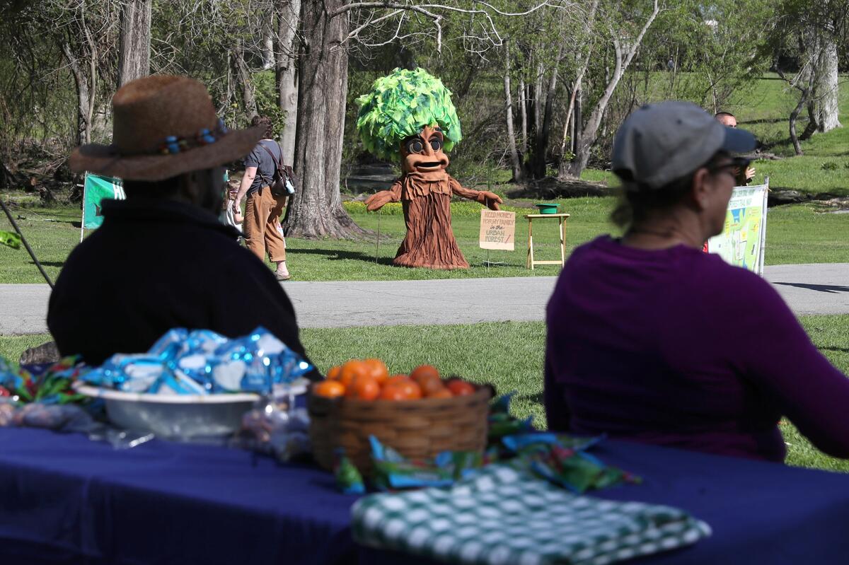 A tree character mascot stands ready as part of Friday's celebration at Central Park in Huntington Beach.