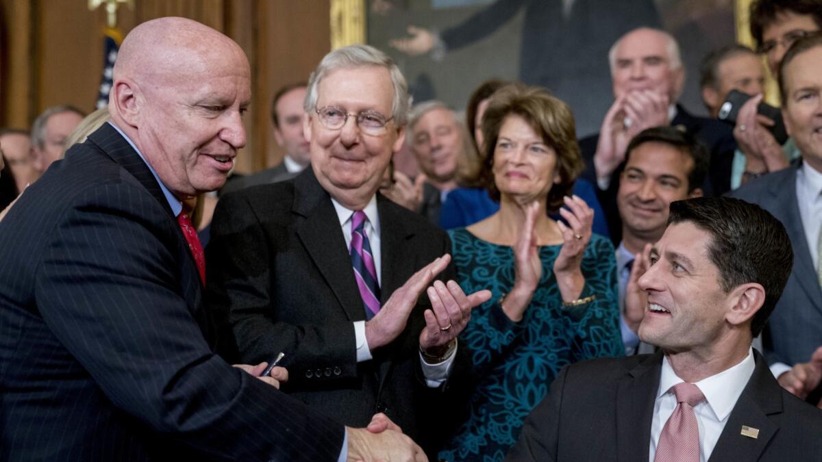Then-House Speaker Paul Ryan (R-Wis.), right, congratulates then-Ways and Means Committee Chairman Kevin Brady (R-Texas), left, as Senate Majority Leader Mitch McConnell (R-Ky.) looks on after passing the GOP tax bill in December 2017.