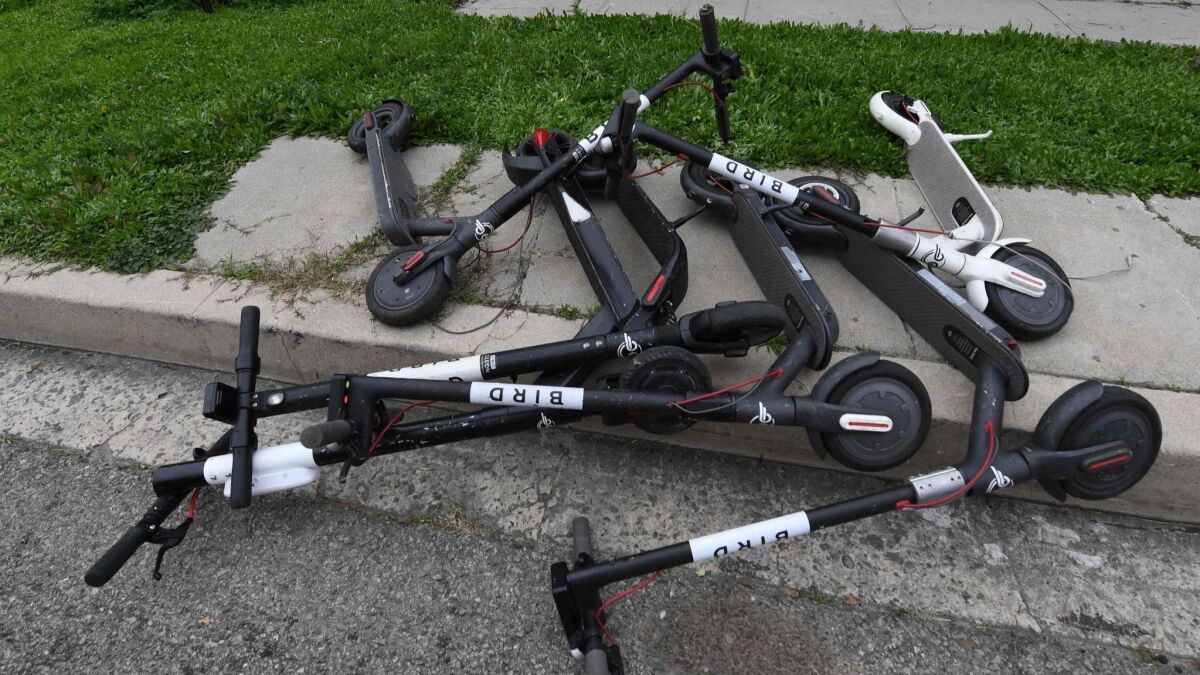 Scooters lie on a sidewalk in Los Angeles. One part-time mechanic said he could make $400 on a good day repairing the vehicles.