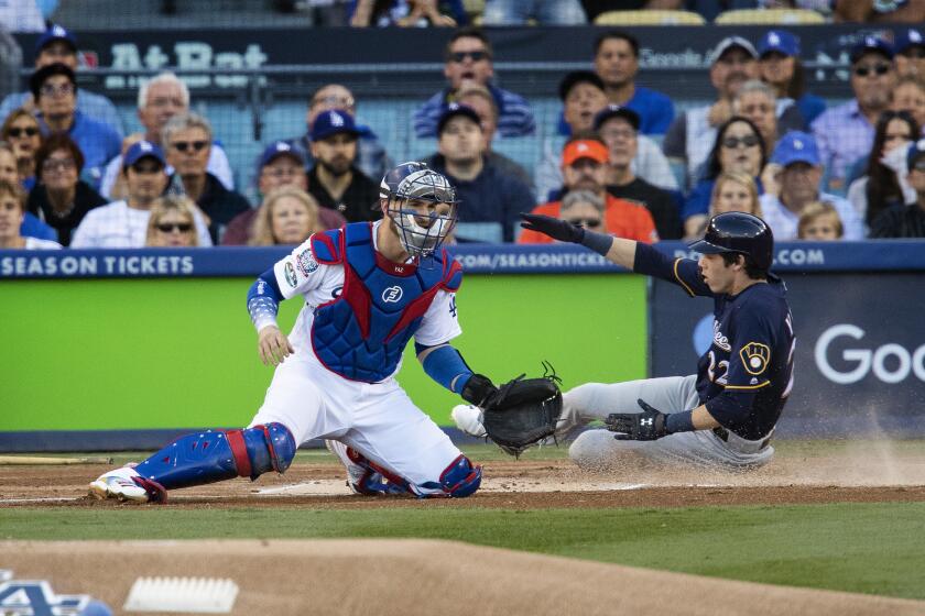 Brewers right fielder Christian Yelich slides past Dodgers catcher Yasmani Grandal to score the first run of the game on a double by Ryan Braun in the first inning of NLCS Game 3.