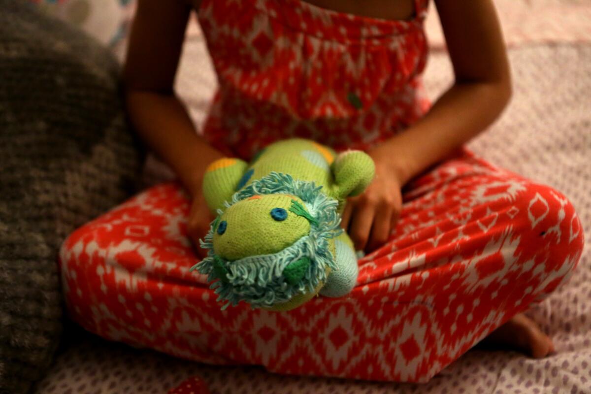 T plays with "Liony," her favorite stuffed animal. (Genaro Molina / Los Angeles Times)