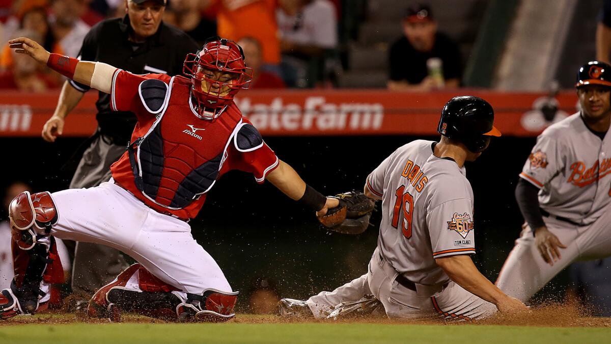 Baltimore's Chris Davis scores past Angels catcher Hank Conger on a double by teammate J.J. Hardy (not pictured) during the sixth inning of the Angels' 4-2 loss Tuesday.