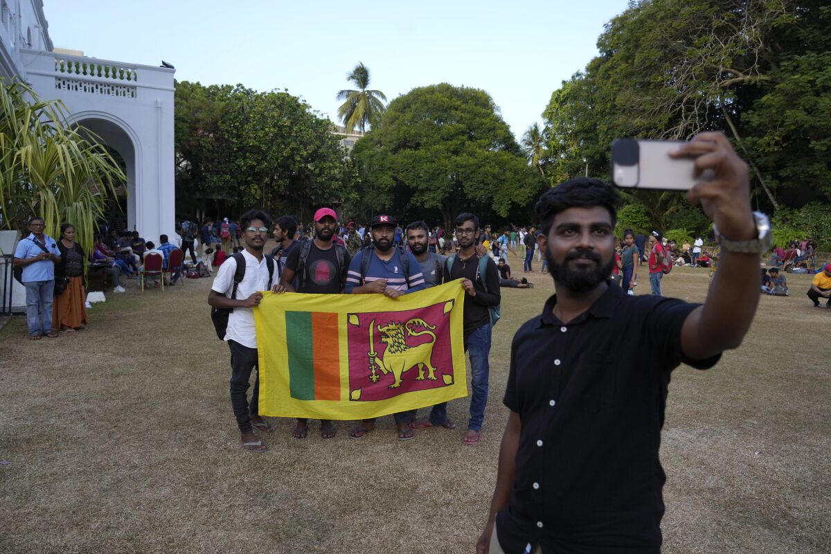People take selfie at the official residence of president Gotabaya Rajapaksa fourth days after it was stormed by anti government protesters in Colombo in Colombo, Sri Lanka, Wednesday, July 13, 2022. The president of Sri Lanka fled the country early Wednesday, days after protesters stormed his home and office and the official residence of his prime minister amid a monthslong economic crisis that triggered severe shortages of food and fuel.(AP Photo/Rafiq Maqbool)