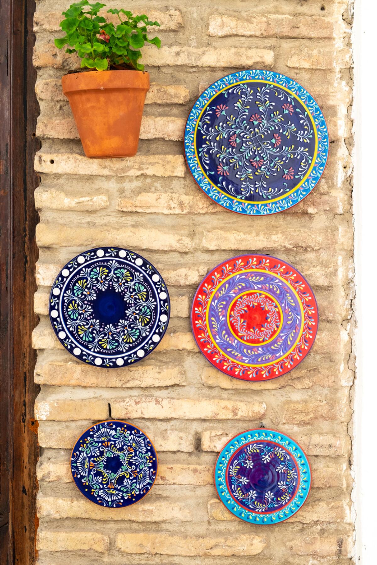 A collection of plates hangs on a narrow wall.