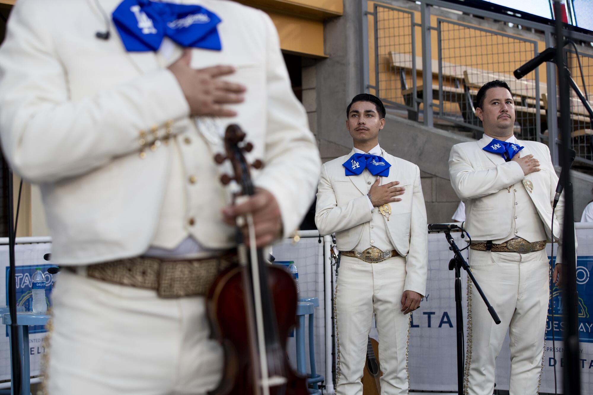Mariachi Garibaldi de Jaime Cuellar members place their hands over their hearts during the singing of the National Anthem